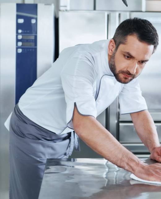 Bearded man prepares the surface for cooking in the kitchen. Cook carefully wipes the surface. Health and safety concept.